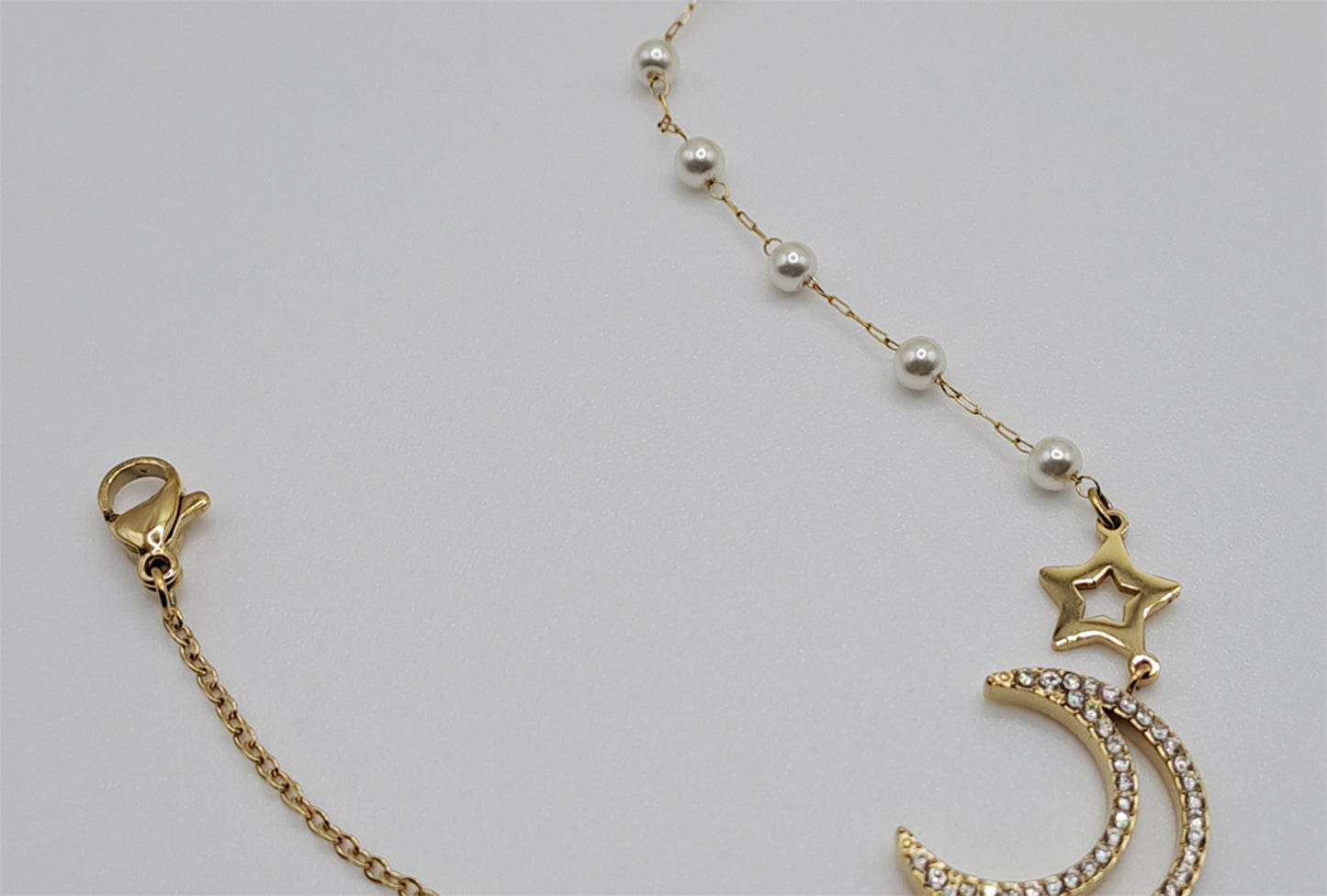 Detalhe pulseira elegante com design lunar, pérolas e zircónias brilhantes sofisticadas