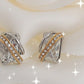 Detalhe dos brincos elegantes com zircónia central e acabamento prateado dourado
